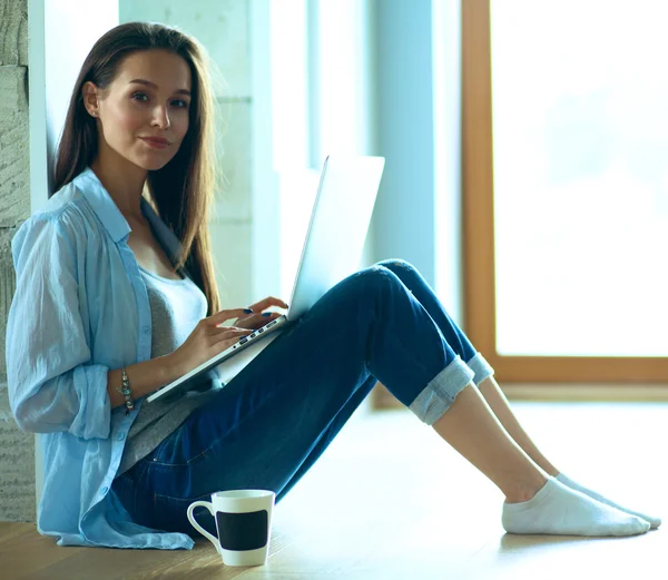 Unga vackra kvinnan hemma sitter på golvet med laptop — Stockfoto