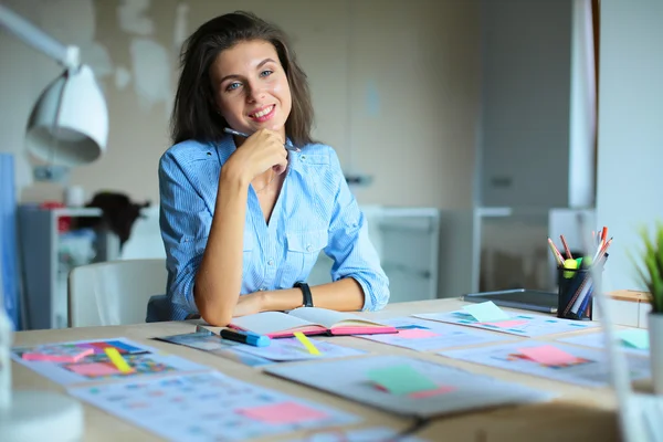 Jonge vrouw zit aan het bureau met instrumenten, plan en laptop — Stockfoto