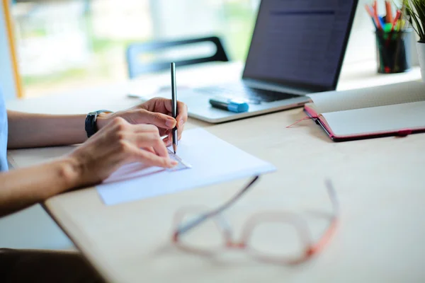 Young woman sitting at the desk with instruments, plan and laptop — Stock Photo, Image