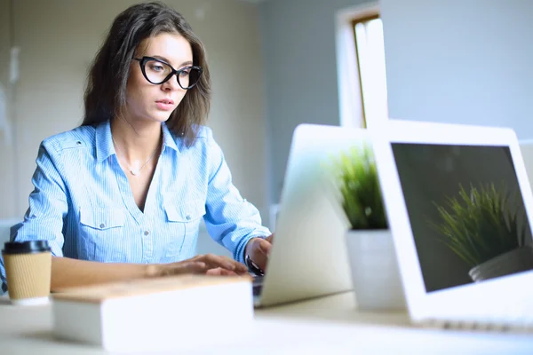 若い女性がオフィスのテーブルに座ってノートパソコンの画面を見て . — ストック写真