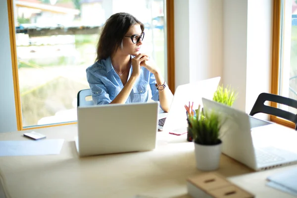 Mujer joven sentada en la mesa de la oficina con portátil — Foto de Stock