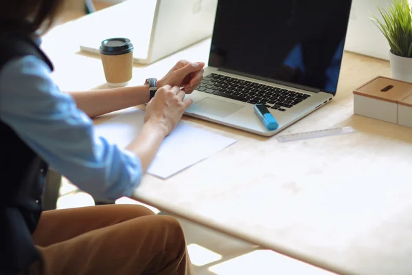 Jovem mulher sentada à mesa do escritório, olhando para a tela do computador portátil  . — Fotografia de Stock