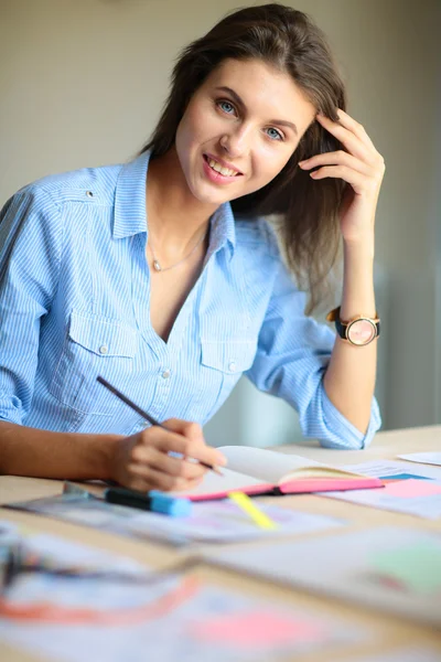 Mujer joven sentada en el escritorio con instrumentos, plano y portátil —  Fotos de Stock