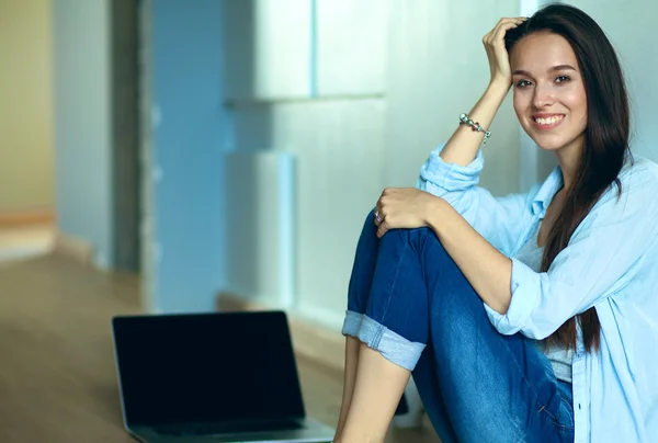 Giovane bella donna a casa seduta sul pavimento con il computer portatile — Foto Stock