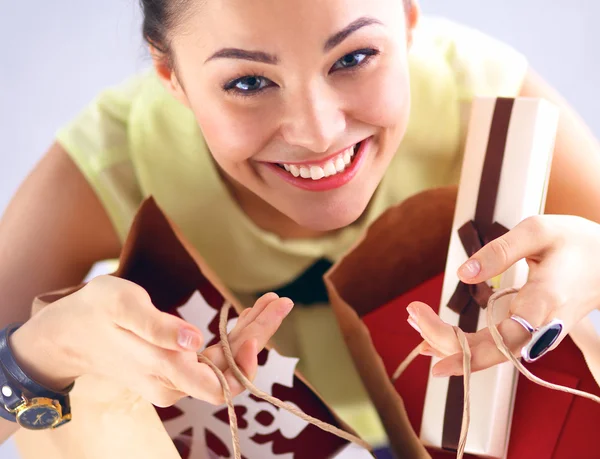 Gülümseyen kadın Noel hediyeleri ile izole kırmızı zemin üzerine — Stok fotoğraf