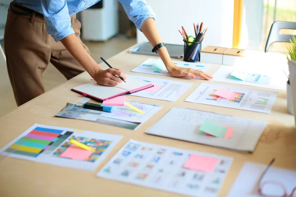 Jonge vrouw in de buurt van bureau met instrumenten, plan en laptop — Stockfoto