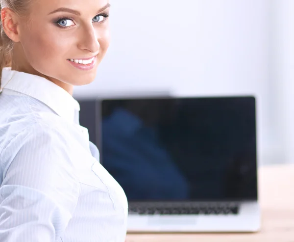 Aantrekkelijke zakenvrouw zit op een bureau met laptop in het kantoor — Stockfoto