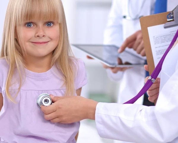 Female doctor examining child with stethoscope at surgery — Stock Photo, Image