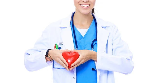 Positive female doctor standing with stethoscope and red heart symbol isolated — Stock Photo, Image