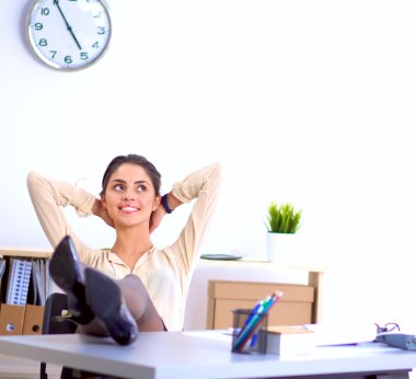 İş kadını ellerini başının arkasına koyup bir ofis sandalyesinde oturuyor.