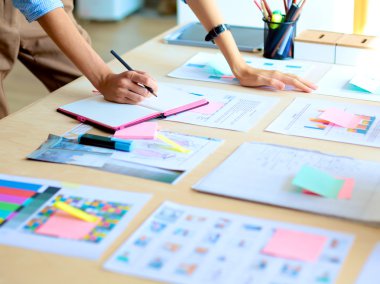 Enstrümanlar, planlar ve dizüstü bilgisayarlarla masanın yanında duran genç bir kadın.