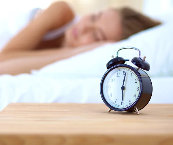 Young sleeping woman and alarm clock in bedroom at home — Stock Photo, Image