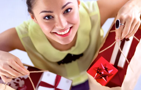 赤の背景に分離したクリスマス プレゼントで女性の笑みを浮かべて、 — ストック写真