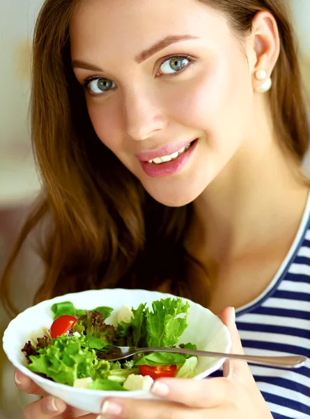 Mladá žena jíst salát a drží míchaný salát — Stock fotografie