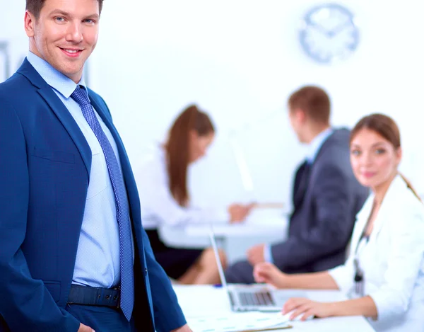 Erfolgreicher Geschäftsmann steht mit seinen Mitarbeitern im Hintergrund im Büro — Stockfoto