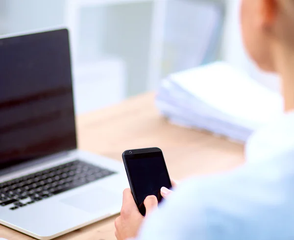 Businesswoman sending message with smartphone sitting in the office — Stock Photo, Image