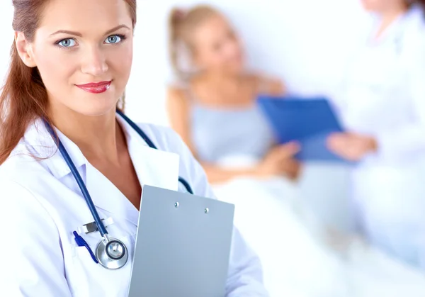 Médico sonriente con una carpeta en uniforme de pie en el hospital — Foto de Stock