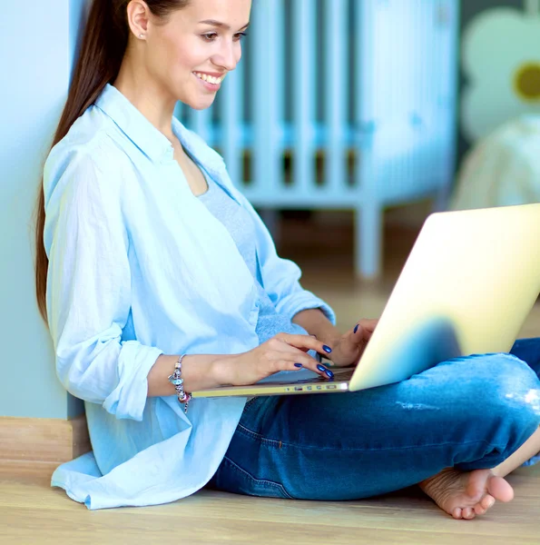 一个年轻的女人在家里的画像坐在地上用的笔记本电脑 — ストック写真