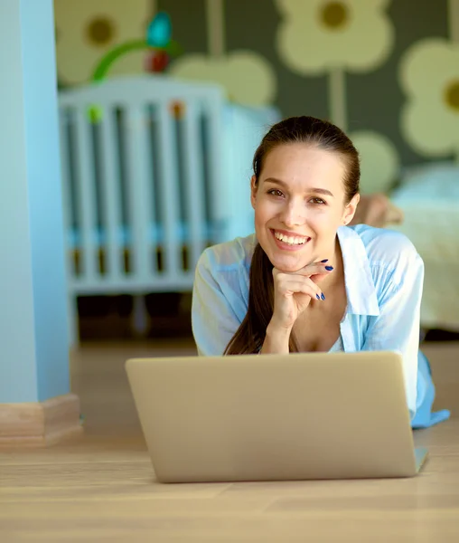 Giovane bella donna a casa seduta sul pavimento con il computer portatile — Foto Stock