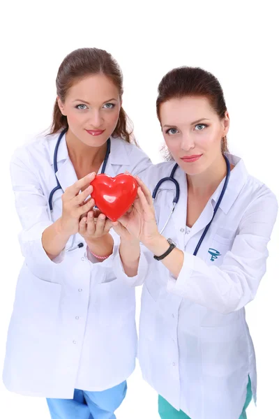 Dos doctora sosteniendo un corazón rojo, aislada sobre fondo blanco — Foto de Stock