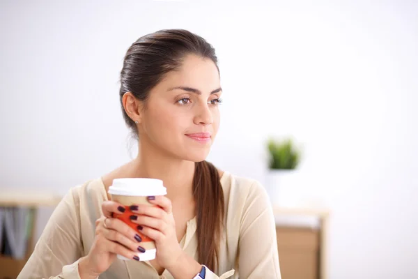 Young businesswoman sitting on the desk with with cup — Stock Photo, Image