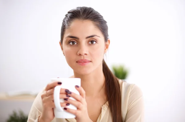 Молодая деловая женщина сидит на столе с чашкой — стоковое фото