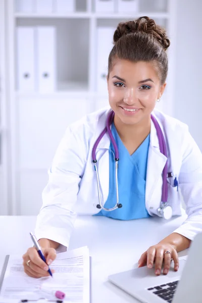 Female doctor sitting on the desk and working a laptop — Stock Photo, Image