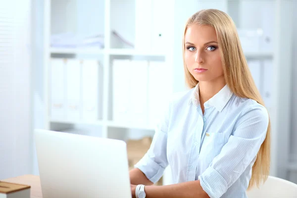 Aantrekkelijke zakenvrouw zit op een bureau met laptop in het kantoor — Stockfoto