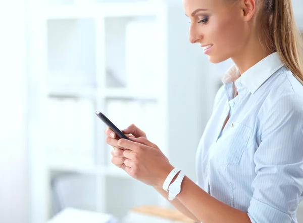 Businesswoman sending message with smartphone in office — Stock Photo, Image