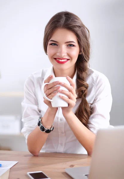 Junge Geschäftsfrau sitzt mit Tasse auf dem Schreibtisch — Stockfoto