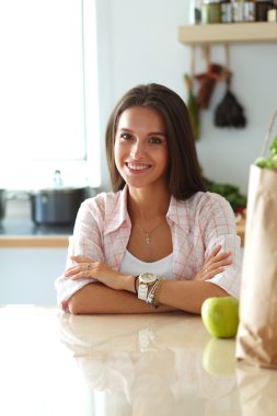 Mutfakta yemek yapmak için tablet bilgisayar kullanan genç bir kadın. .
