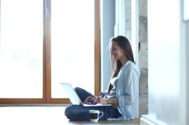 genç güzel kadın evde laptop ile katta oturuyor.