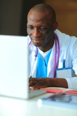 Masada dizüstü bilgisayarda çalışan genç bir Afrikalı doktor.