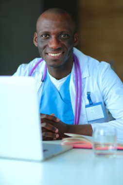 Masada dizüstü bilgisayarda çalışan genç bir Afrikalı doktor.