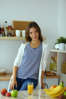 Mutfakta masanın yanında duran genç bir kadın.