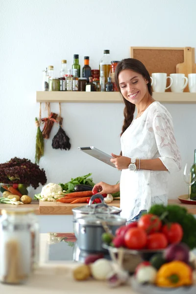 Young woman using a tablet computer to cook in her kitchen . — Stock Photo, Image