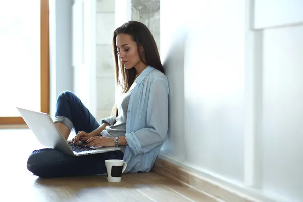 Unga vackra kvinnan hemma sitter på golvet med laptop — Stockfoto