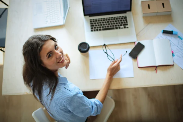 Giovane donna seduta al tavolo dell'ufficio con computer portatile — Foto Stock