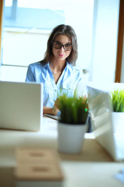 Mladá žena sedí u kancelářského stolu s notebookem — Stock fotografie