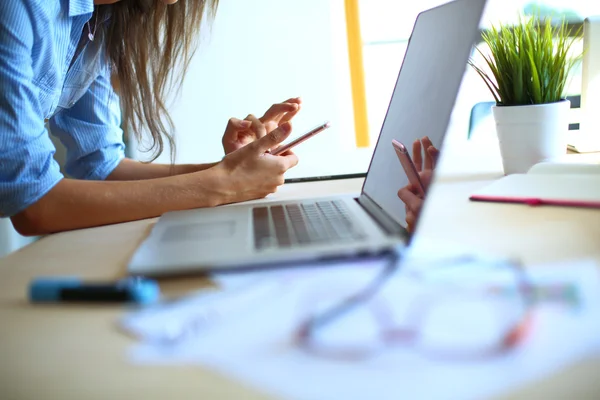 Jeune femme assise au bureau avec instruments, plan et ordinateur portable — Photo