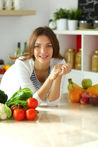 Jonge vrouw zit in de buurt van bureau in de keuken — Stockfoto