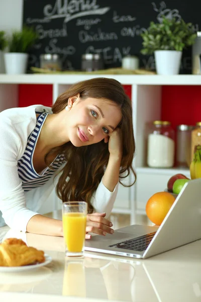 Giovane donna seduta vicino alla scrivania in cucina — Foto Stock