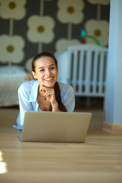 Unga vackra kvinnan hemma sitter på golvet med laptop — Stockfoto