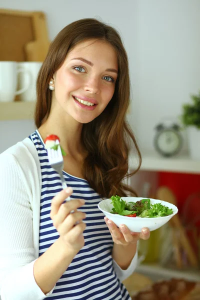 Молода жінка їсть салат і тримає змішаний салат — стокове фото