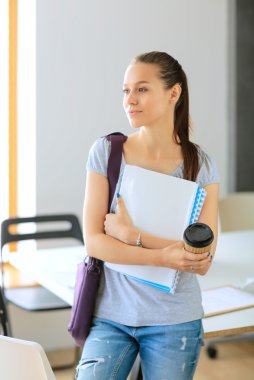 Klasörler ve kahve ile gülümseyen öğrenci