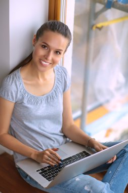 Genç ve güzel bir kadın evde dizüstü bilgisayar kullanıyor.