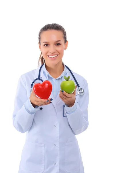 Beautiful smiling female doctor holding red heart and green apple — Stock Photo, Image