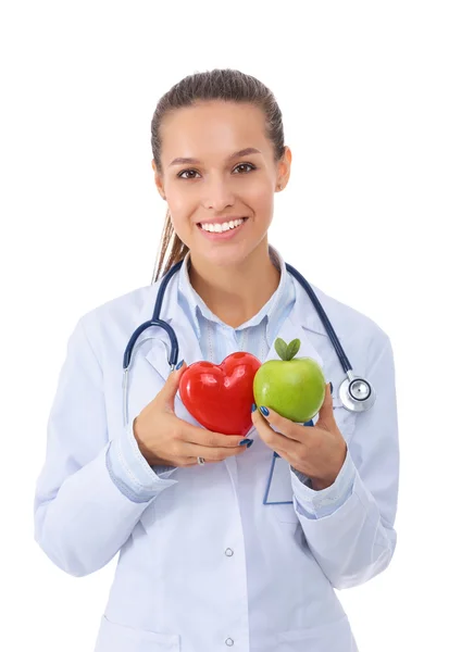 Beautiful smiling female doctor holding red heart and green apple — Stock Photo, Image