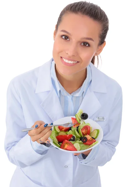 Porträtt av en vacker kvinna läkare som håller en tallrik med färska grönsaker. — Stockfoto