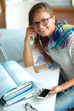 Kitapların arasında masa başında oturan genç bir kadın.